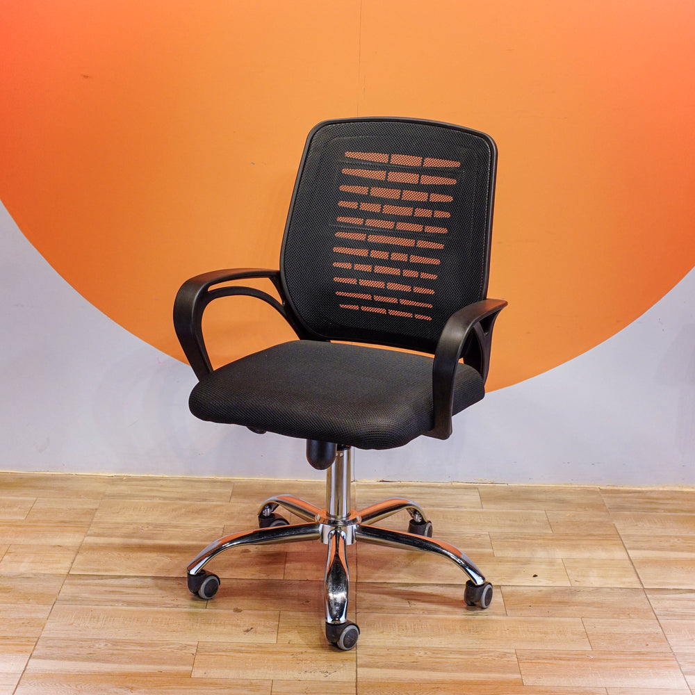 Black office chair with mesh back against an orange and gray wall.