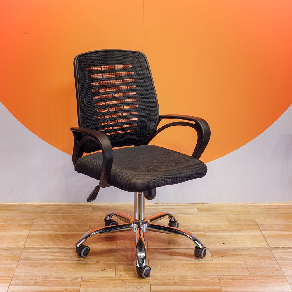 Black office chair with mesh back against an orange and gray wall.