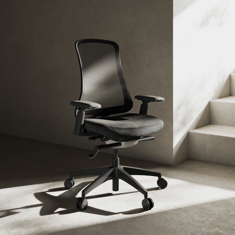 Neva Furniture Sheer ergonomic office chair with black mesh back and gray fabric seat, adjustable armrests, and wheeled base.