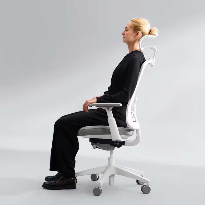 Neva Furniture Sheer ergonomic office chair in white with grey seat, featuring adjustable armrests and headrest, shown with a woman sitting.