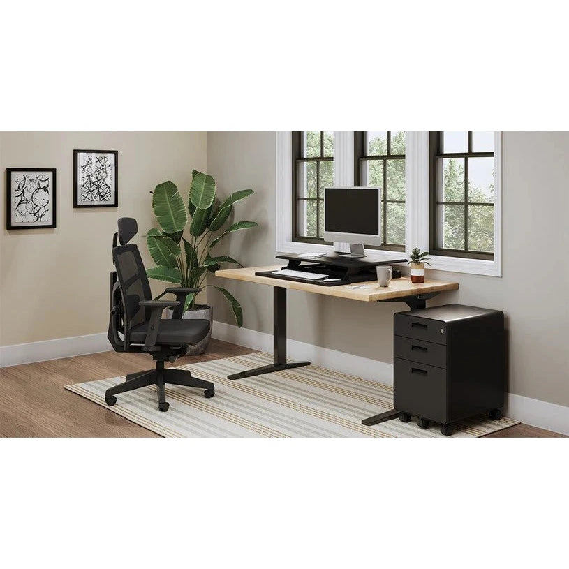 Merryfair Tune black high-back chair beside a standing desk, monitor, windows and drawer unit
