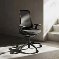 Neva Furniture Sheer ergonomic office chair with black mesh back and gray fabric seat, adjustable armrests, and wheeled base.