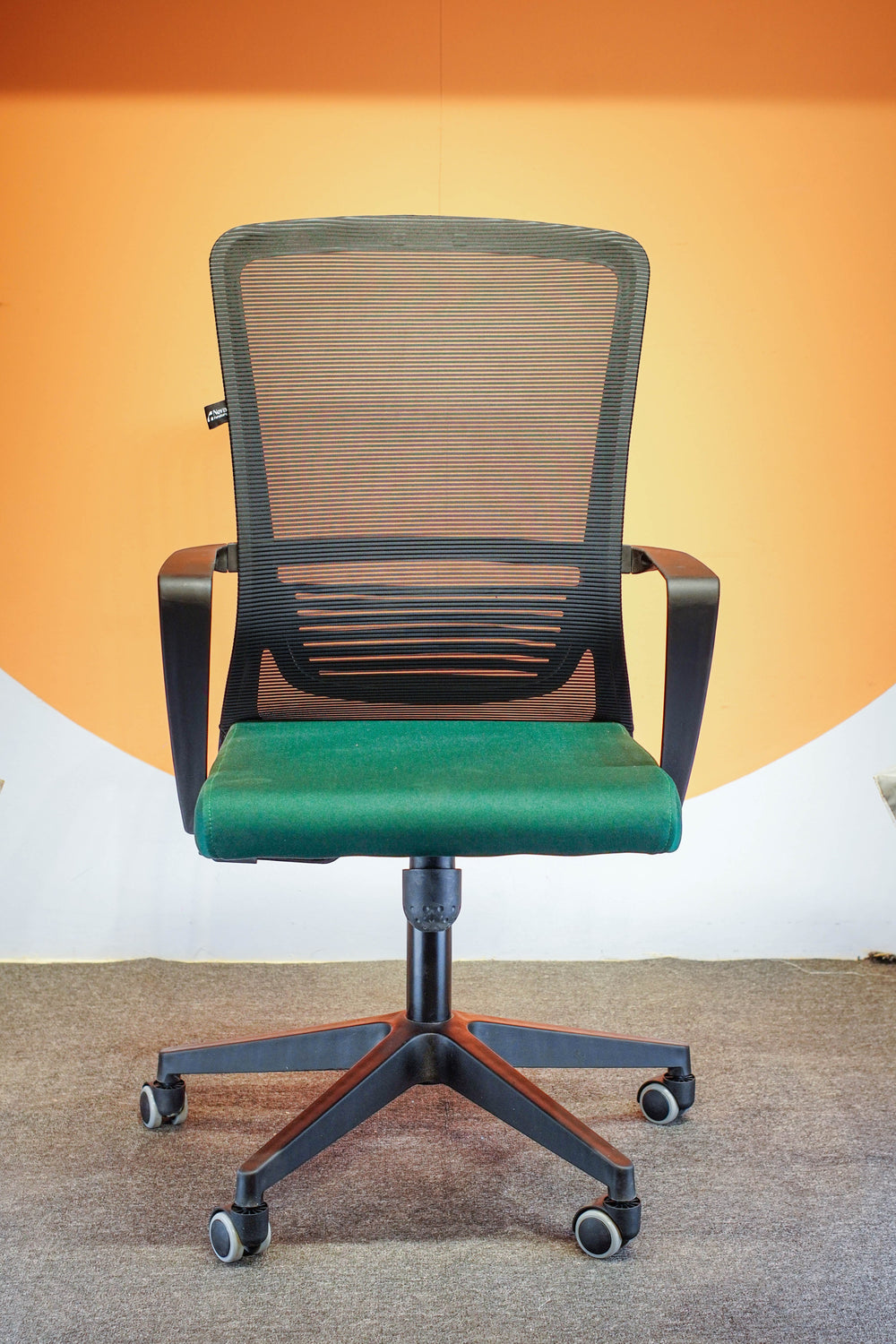 Neva Furniture Vibe Chair with black mesh back and green cushioned seat, featuring adjustable height and tilt lock.